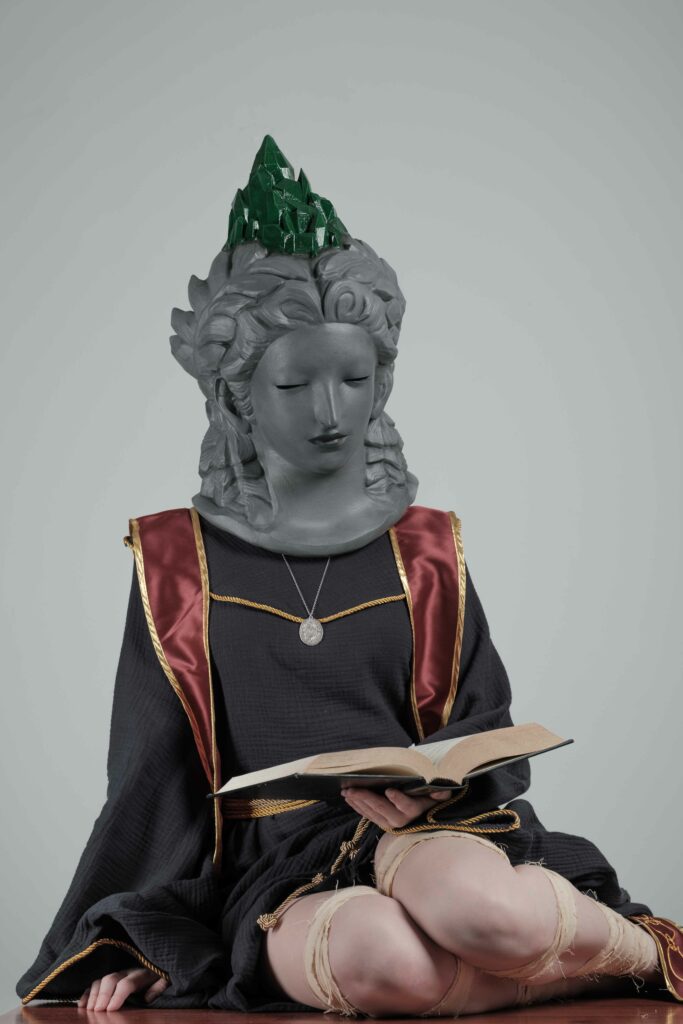 Sellen holding a book. button over the image that says details. The button will take you to a place that will talk about the making of the Sellen cosplay