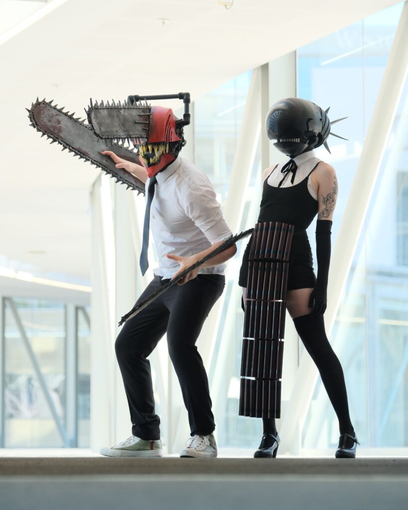 Bomb Devil cosplayer standing next to a Chainsaw man cosplayer.