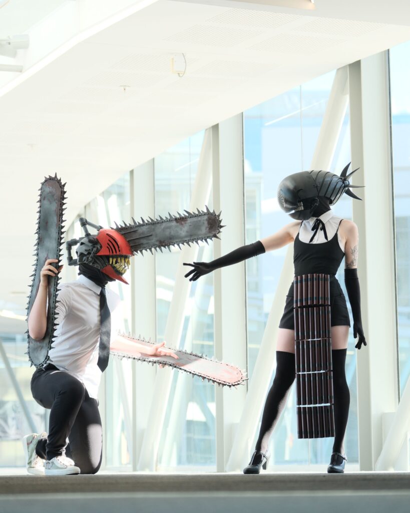 Domb devil cosplayer reach hand out to Chainsaw Man cosplayer.