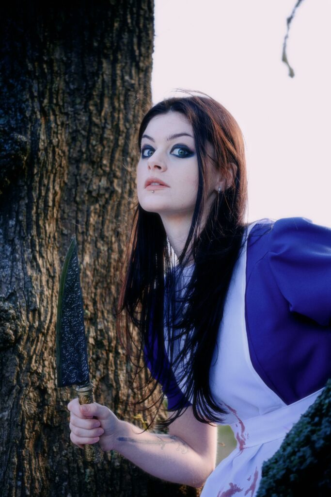 Alice cosplayer from Alice madness holding a knife while being scary
